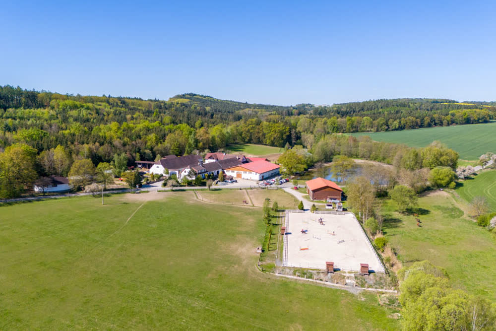 Der Hof mit Reitbahn und den Wäldern ringsum